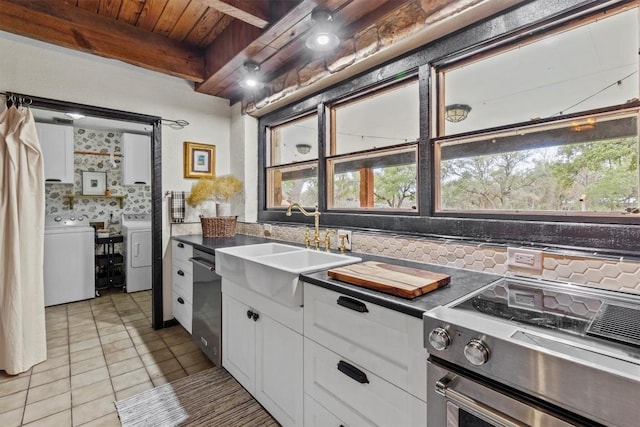 kitchen with stainless steel appliances, a sink, white cabinetry, independent washer and dryer, and beam ceiling