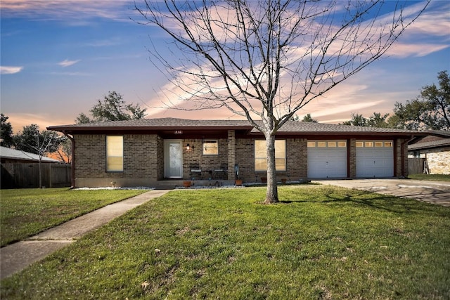 ranch-style home featuring driveway, brick siding, a lawn, and an attached garage