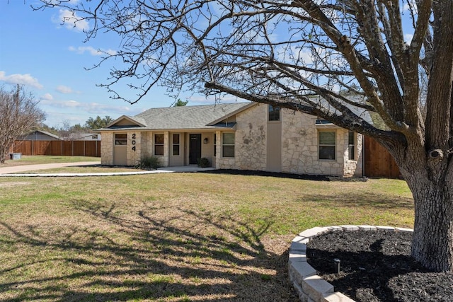 view of front of house with stone siding, roof with shingles, a front lawn, and fence