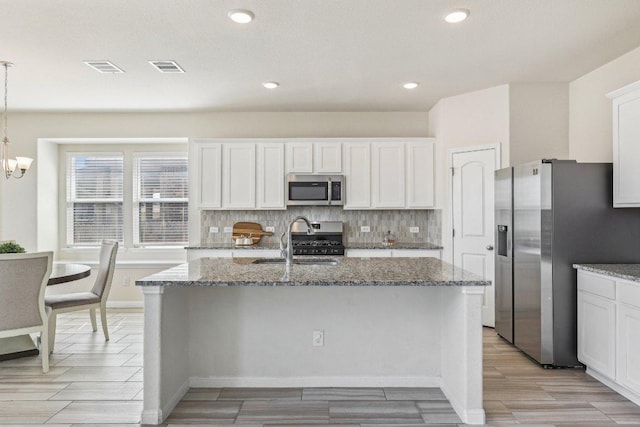 20417 Whimbrel Ct, Pflugerville, TX 78660 - kitchen featuring appliances with stainless steel finishes, a sink, dark stone countertops, decorative backsplash, and white cabinets