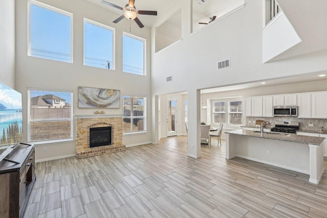 20417 Whimbrel Ct, Pflugerville, TX 78660 - living room featuring ceiling fan, a towering ceiling, baseboards, a fireplace, and wood tiled floors