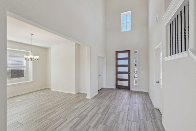 foyer with light wood-type flooring, a wealth of natural light, baseboards, and a notable chandelier