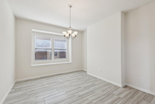 empty room with an inviting chandelier, baseboards, and wood finish floors