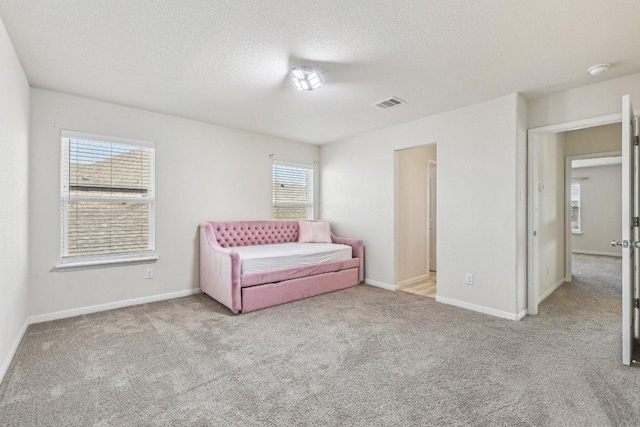 unfurnished room featuring a textured ceiling, carpet floors, visible vents, and baseboards