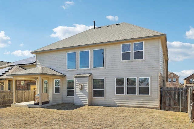 back of property featuring a patio, a shingled roof, a lawn, and a fenced backyard