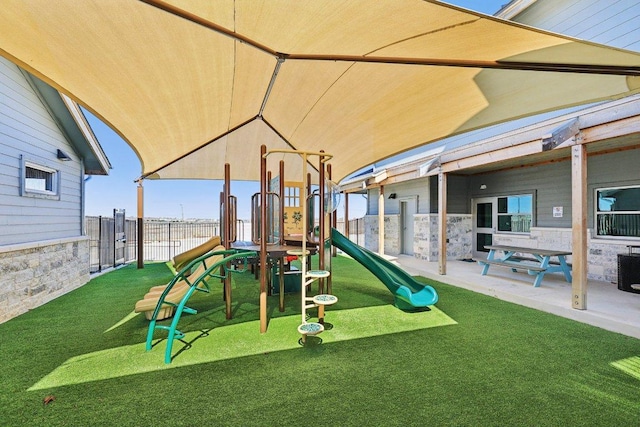 view of play area featuring fence, a lawn, and a patio