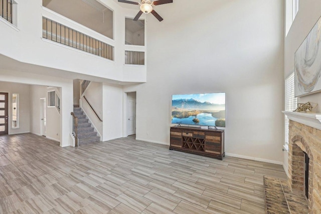 20417 Whimbrel Ct, Pflugerville, TX 78660 - unfurnished living room with a high ceiling, a ceiling fan, stairway, a fireplace, and wood finished floors