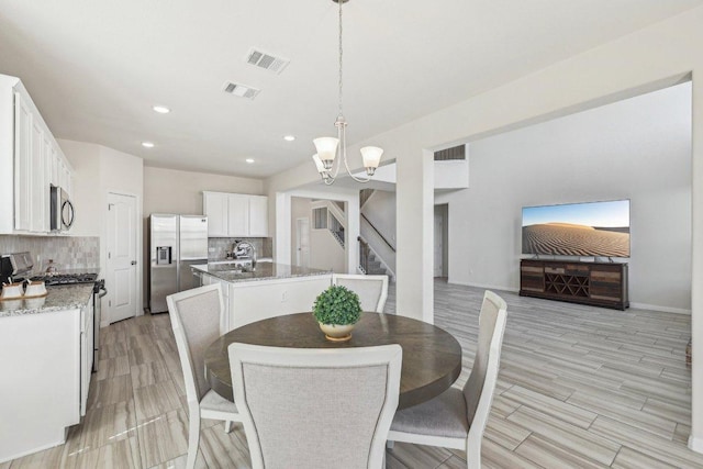 20417 Whimbrel Ct, Pflugerville, TX 78660 - dining area with a chandelier, stairs, recessed lighting, light wood-style flooring, and baseboards
