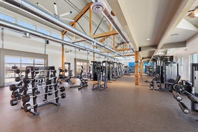 workout area featuring a towering ceiling, a healthy amount of sunlight, and visible vents