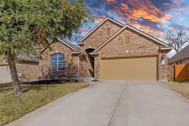 ranch-style home with brick siding, a front yard, fence, a garage, and driveway