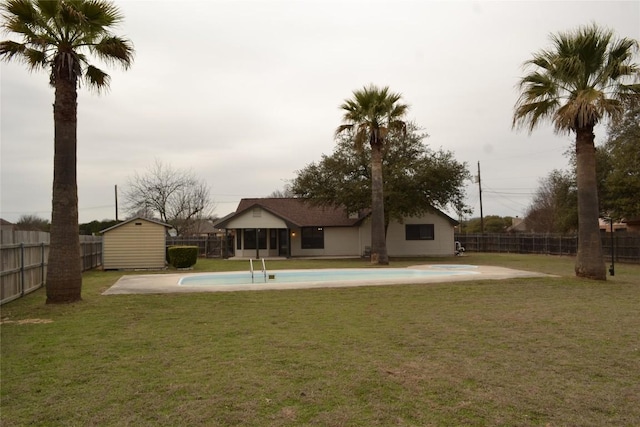 rear view of property featuring an outbuilding, a fenced backyard, a lawn, a fenced in pool, and a shed