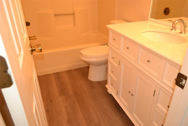 bathroom with toilet, bathing tub / shower combination, wood finished floors, and vanity