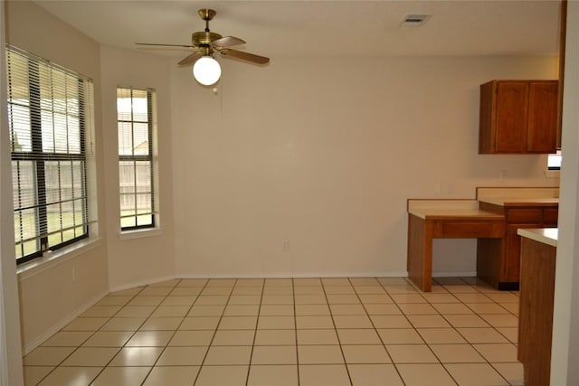 unfurnished dining area featuring ceiling fan, baseboards, a wealth of natural light, and light tile patterned flooring