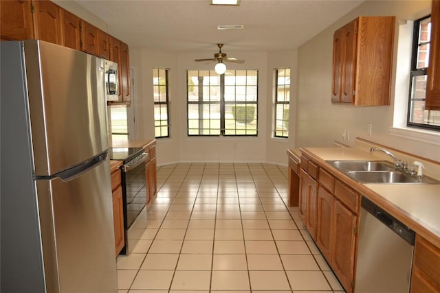 kitchen with light countertops, appliances with stainless steel finishes, light tile patterned flooring, and a sink