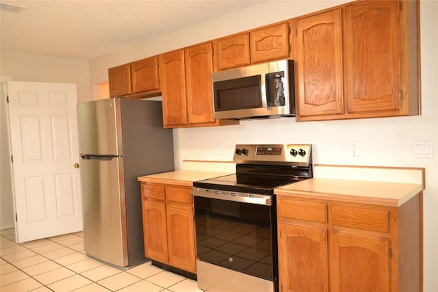 kitchen featuring light tile patterned floors, stainless steel appliances, light countertops, visible vents, and a textured ceiling