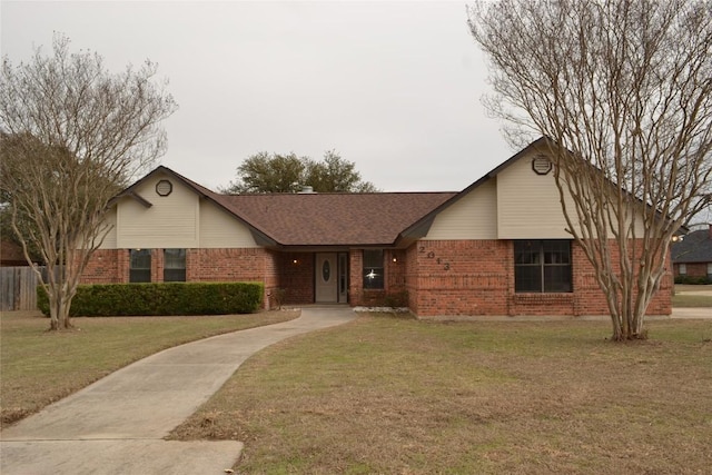 ranch-style house featuring roof with shingles, a front yard, and brick siding