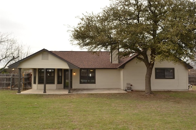 rear view of property with a patio area, a shingled roof, fence, and a yard