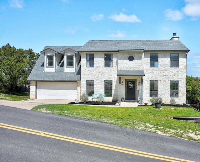 view of front facade with a garage, driveway, a shingled roof, stone siding, and a front yard