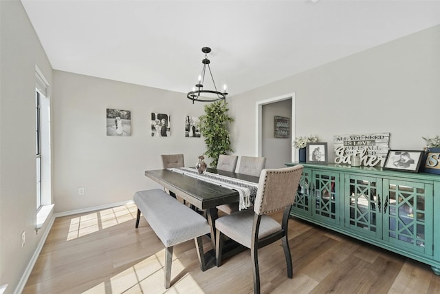 dining space with baseboards, plenty of natural light, a chandelier, and wood finished floors