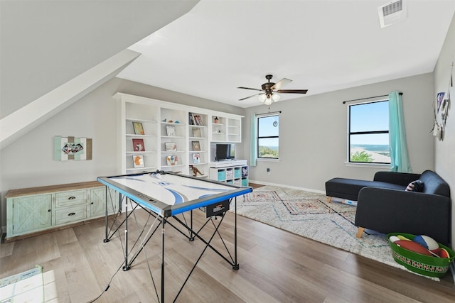 recreation room featuring light wood finished floors, a ceiling fan, visible vents, and baseboards