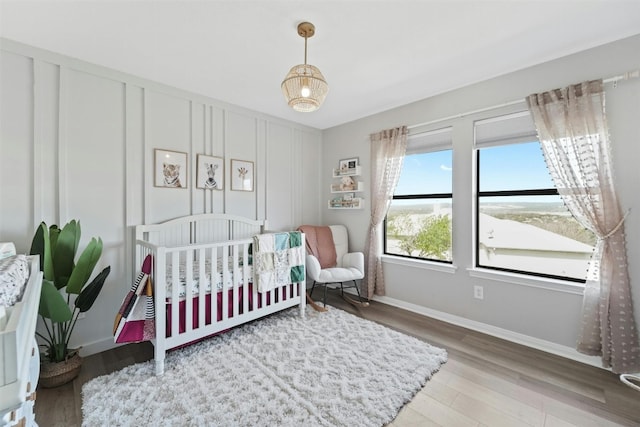 bedroom with baseboards, wood finished floors, and a decorative wall