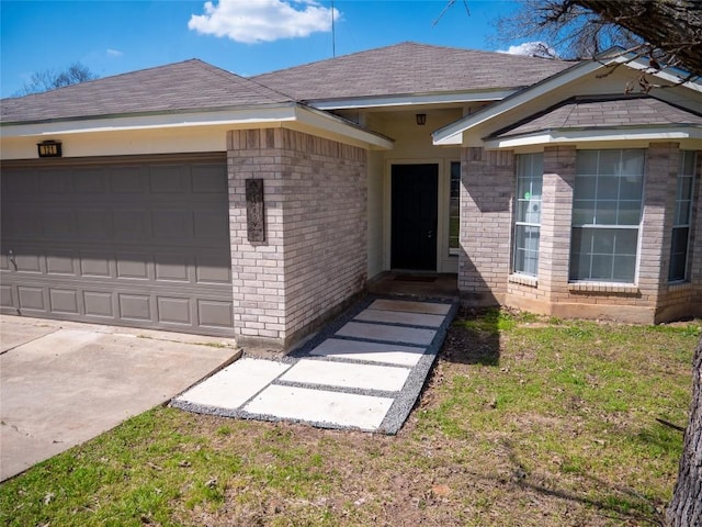 view of front of house featuring an attached garage, a shingled roof, and brick siding