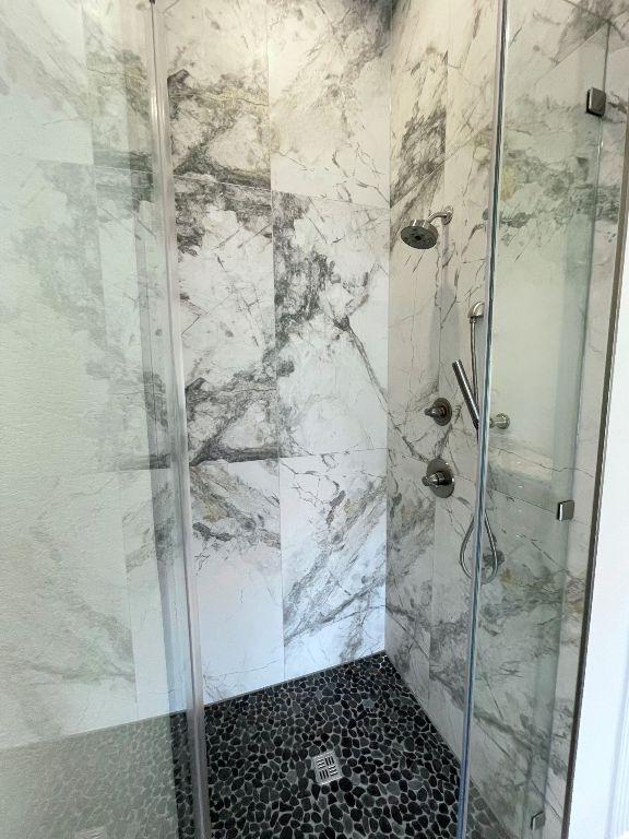 full bathroom with a marble finish shower