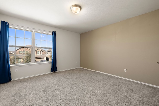 unfurnished room with carpet and baseboards