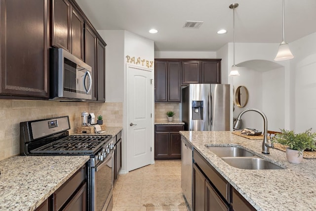 kitchen with stainless steel appliances, visible vents, decorative backsplash, a sink, and dark brown cabinetry