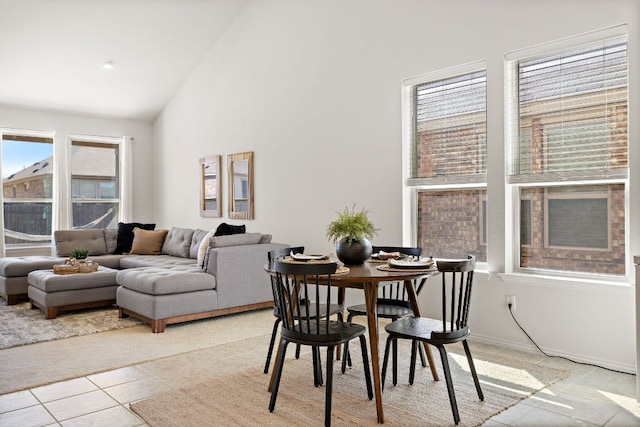 dining room featuring high vaulted ceiling, light tile patterned flooring, and baseboards