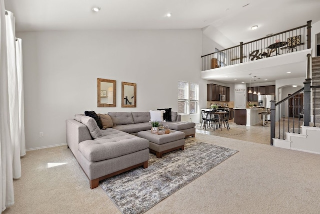 living area featuring high vaulted ceiling, recessed lighting, light colored carpet, baseboards, and stairs