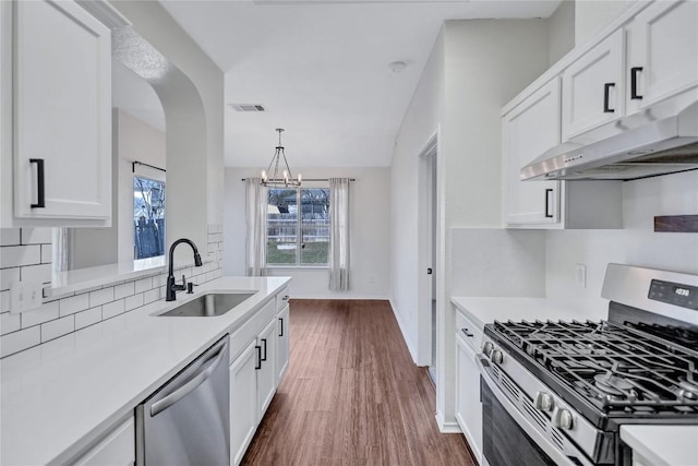 17616 Strontian Pass, Pflugerville, TX 78660 - kitchen featuring appliances with stainless steel finishes, a sink, under cabinet range hood, light countertops, and white cabinetry