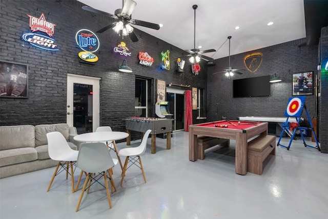 rec room featuring finished concrete flooring, brick wall, and billiards