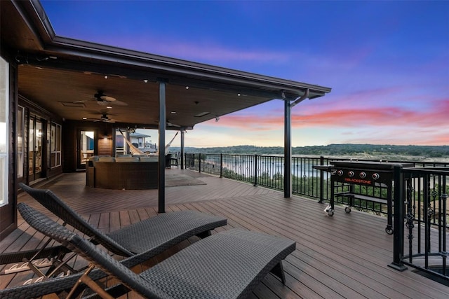 deck at dusk with a water view and ceiling fan