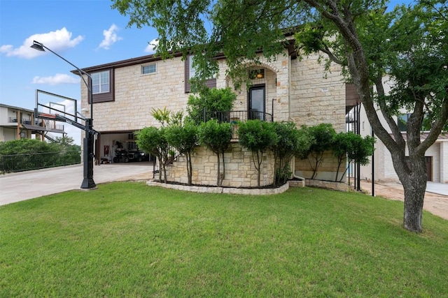 view of front of property with concrete driveway, a front lawn, and stone siding