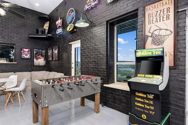 game room with brick wall, ceiling fan, and finished concrete floors