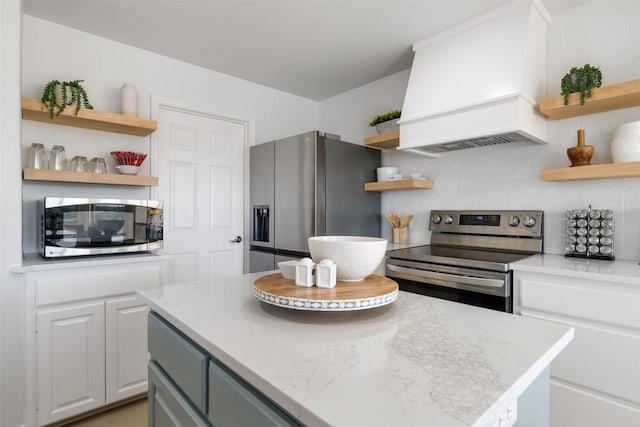 kitchen featuring white cabinets, decorative backsplash, custom exhaust hood, stainless steel appliances, and open shelves