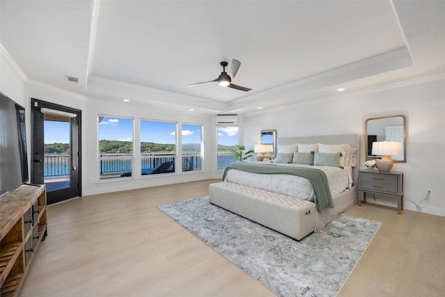 bedroom with access to exterior, light wood finished floors, a raised ceiling, ornamental molding, and an AC wall unit