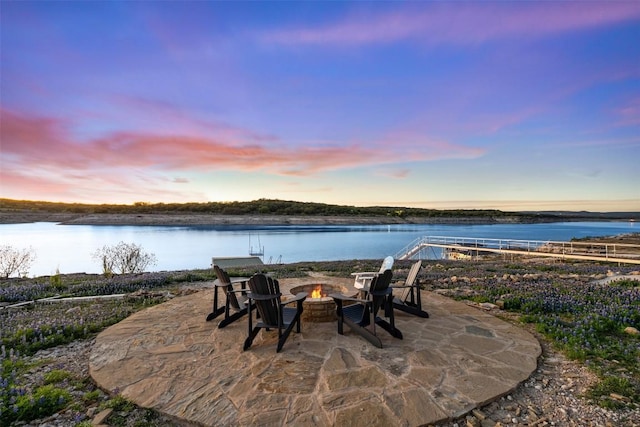 patio terrace at dusk featuring a water view and an outdoor fire pit