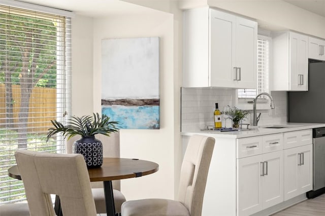 kitchen featuring white cabinets, light countertops, backsplash, and a healthy amount of sunlight