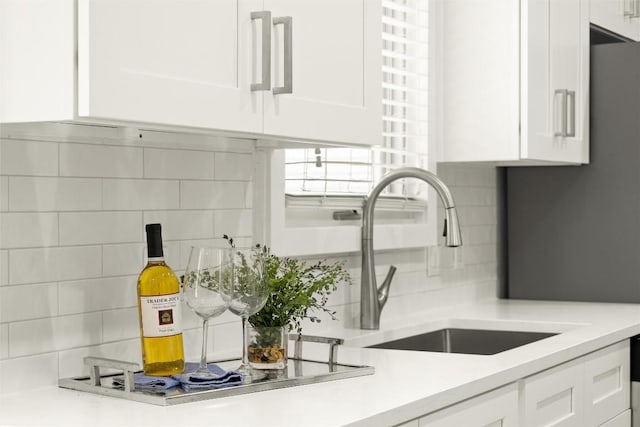 kitchen with light countertops, a sink, and white cabinetry