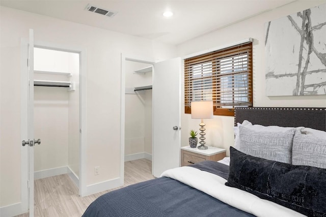 bedroom featuring baseboards, visible vents, a walk in closet, light wood-type flooring, and recessed lighting