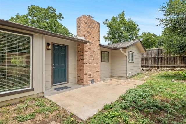 doorway to property with brick siding, a chimney, a patio area, and fence