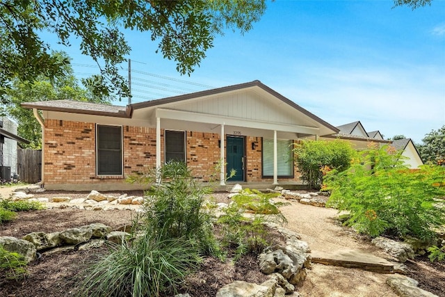 ranch-style house with covered porch, brick siding, and fence