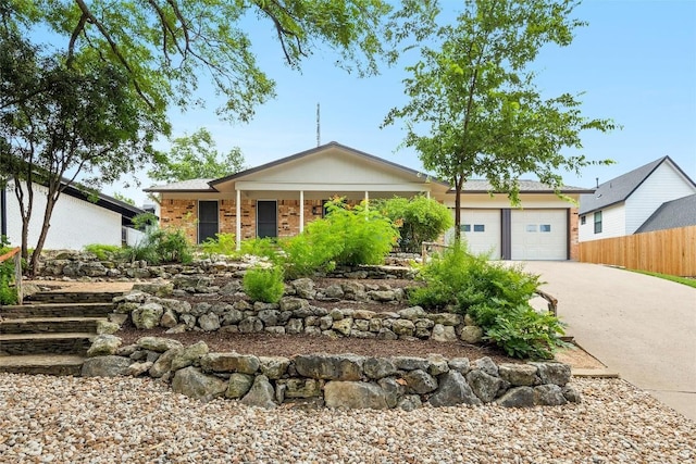 single story home with a garage, driveway, brick siding, and fence