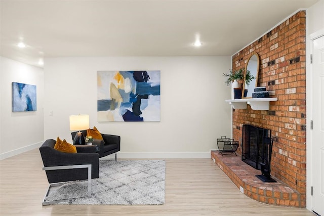 living room featuring a brick fireplace, baseboards, wood finished floors, and recessed lighting