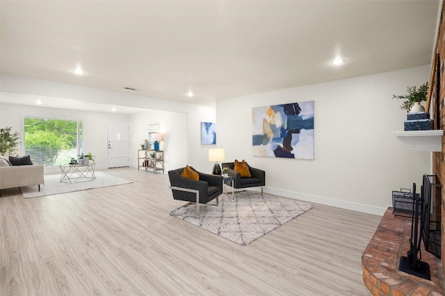 living area featuring visible vents, baseboards, wood finished floors, a fireplace, and recessed lighting