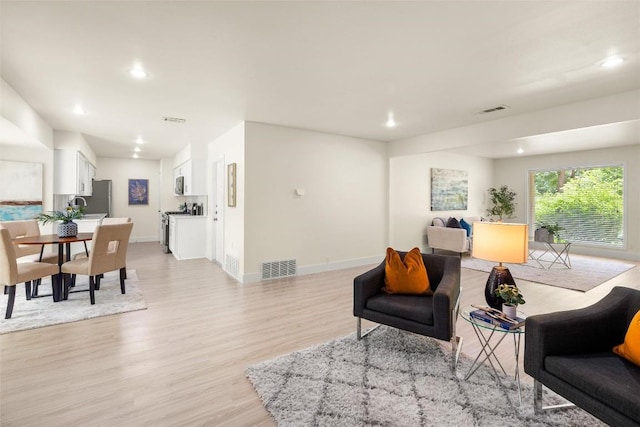 living area with light wood-style floors, visible vents, and baseboards