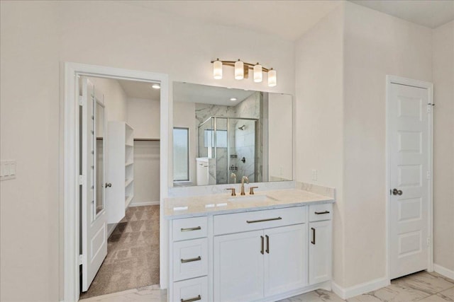 bathroom featuring marble finish floors, a shower stall, vanity, baseboards, and a closet