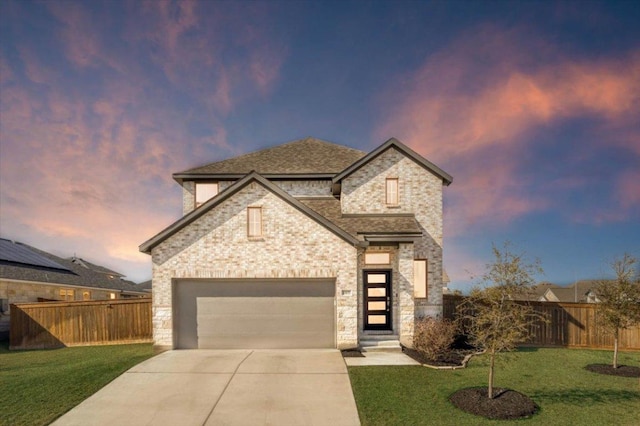 french provincial home featuring a front yard, concrete driveway, fence, and an attached garage